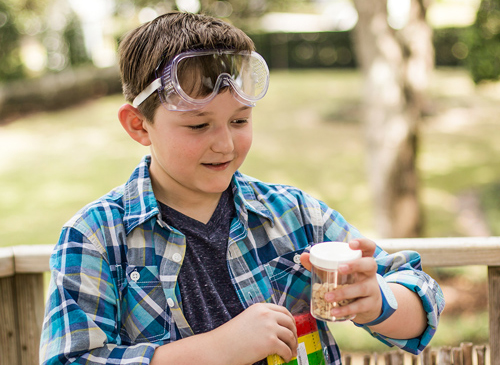 Boy with goggles on his head working on a science experiment outside