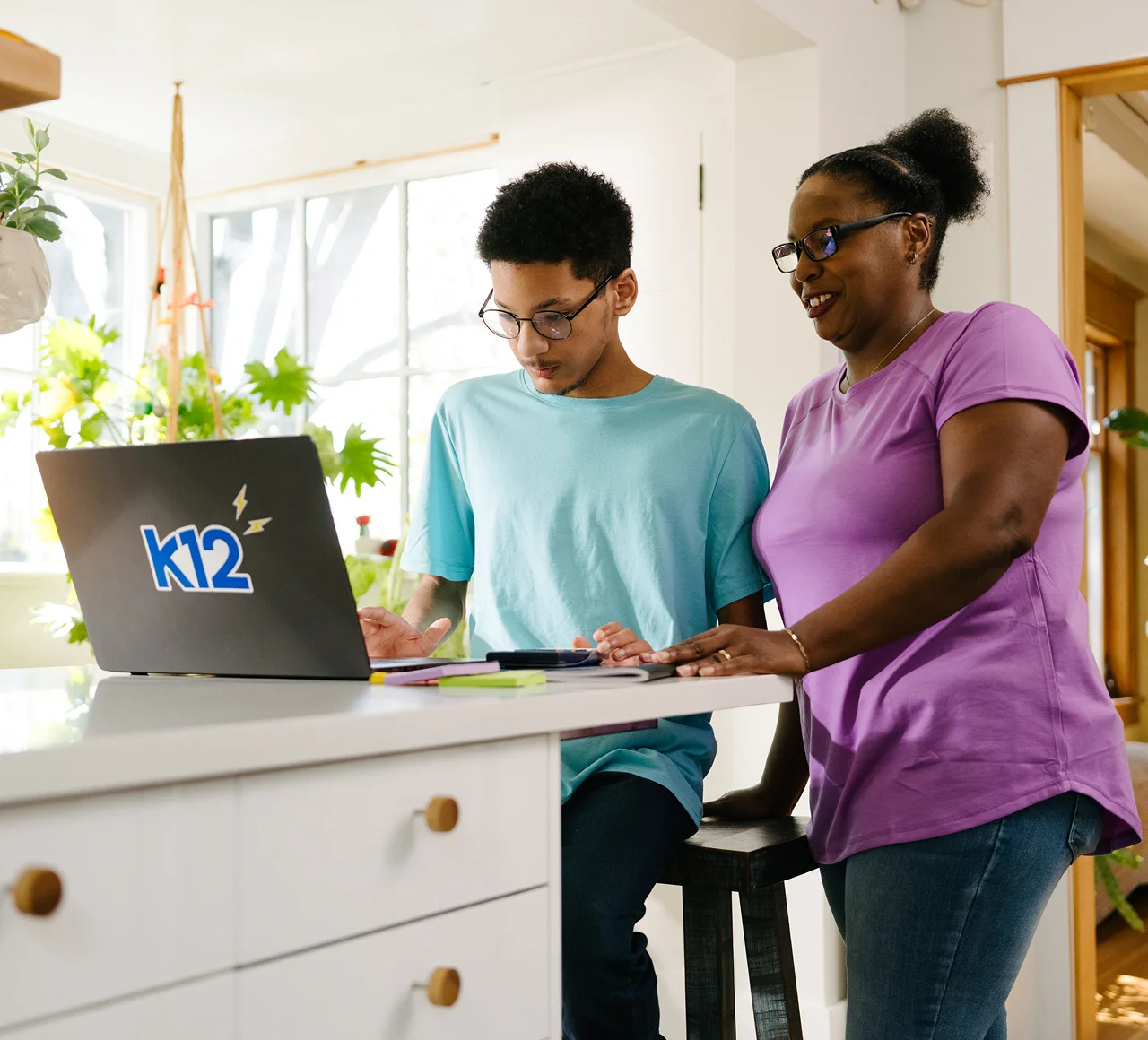 Mother and her son working together at home with their K12 laptop
