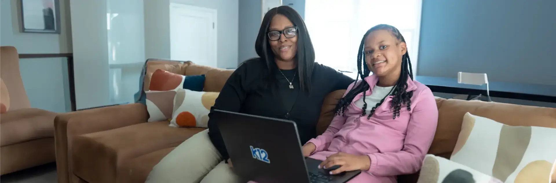 Mother and daughter working together with their laptop at home