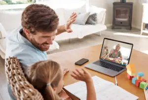Father and her daughter working together with their laptop at home
