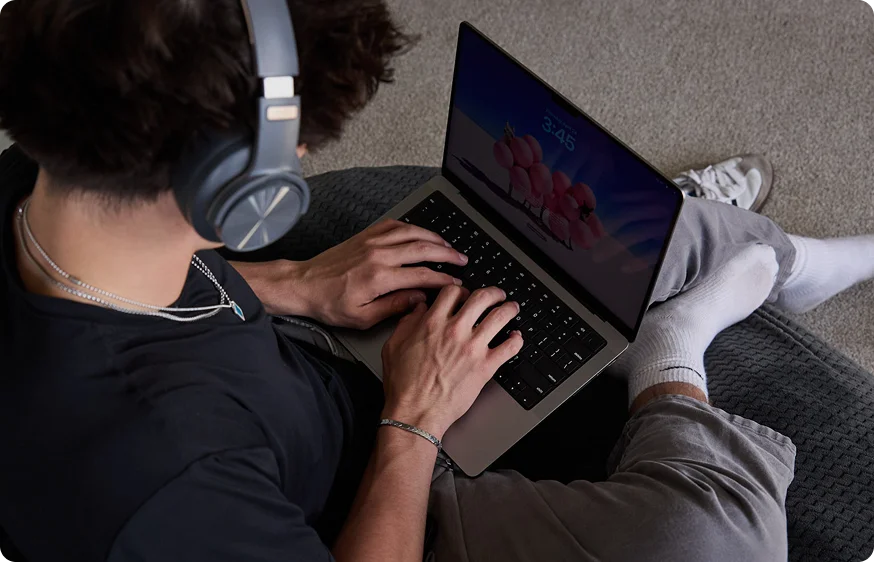 Student wearing a pair of headphones working with his laptop