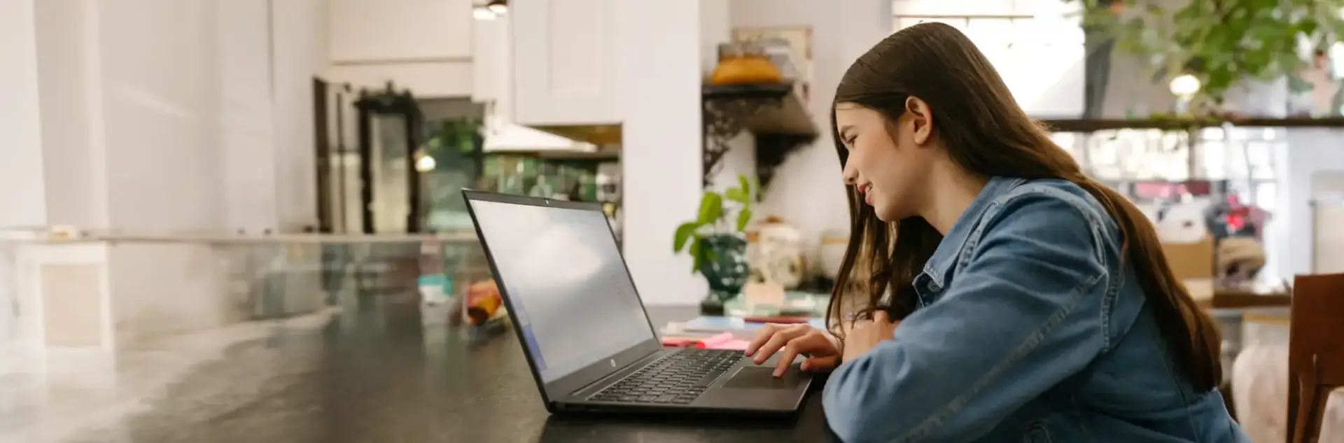 Student working with her laptop at home wearing a denim shirt